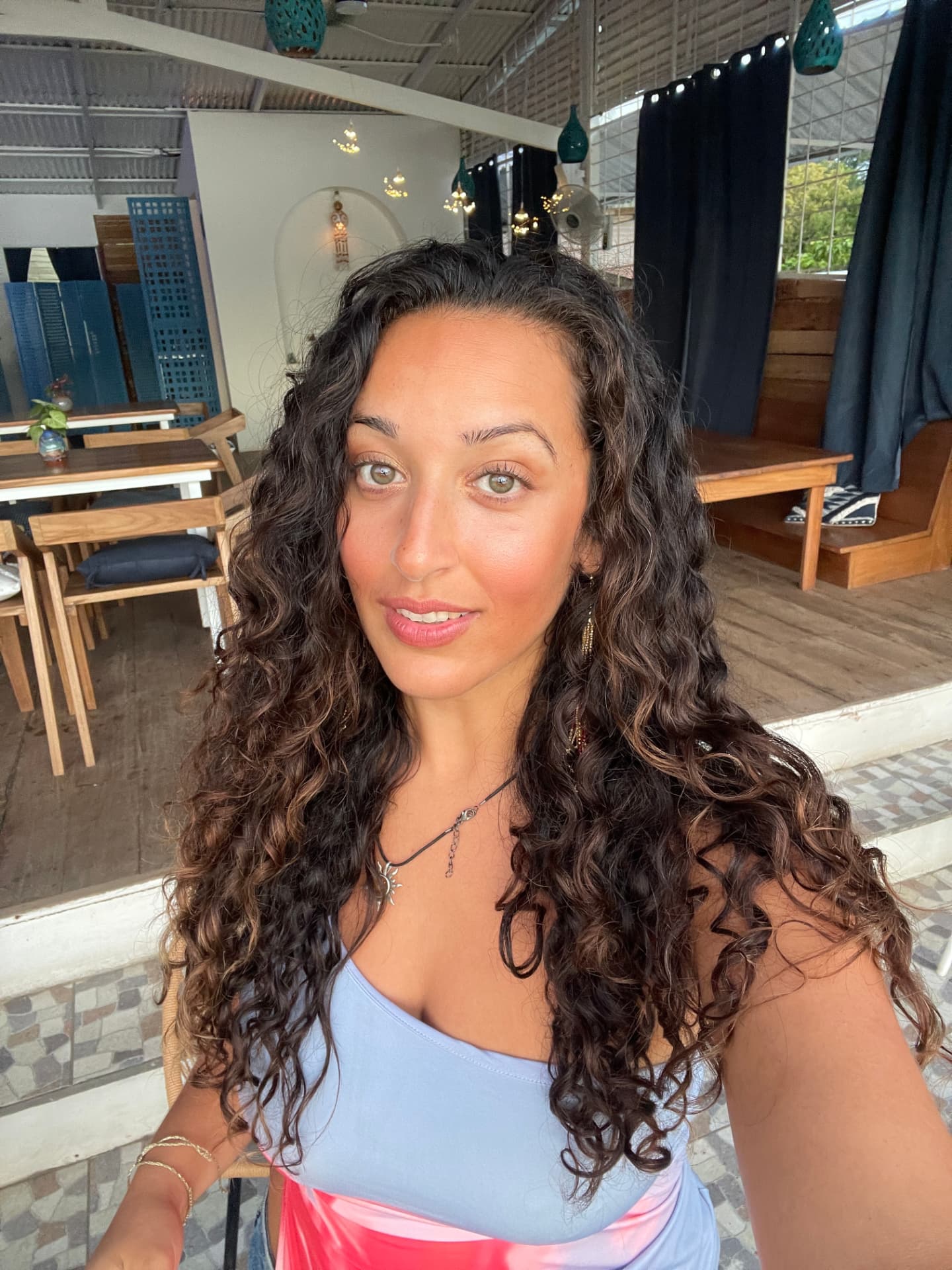 Nora Abou-Dabous smiling in a sunlit outdoor café