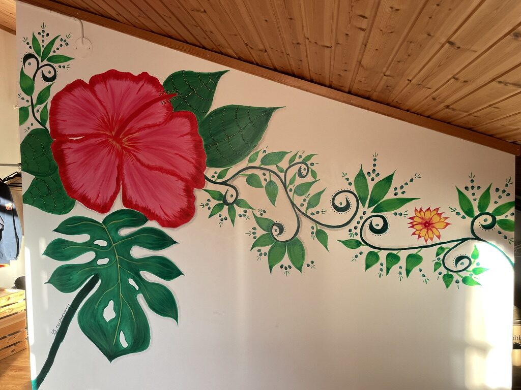 A painted hibiscus and trailing vine following a sloping interior wall